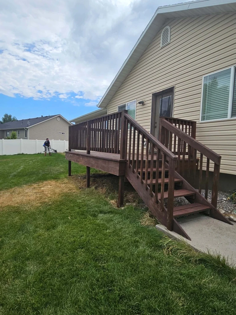 Fully refinished deck and stairs freshly stained deep brown against the tan siding of the home