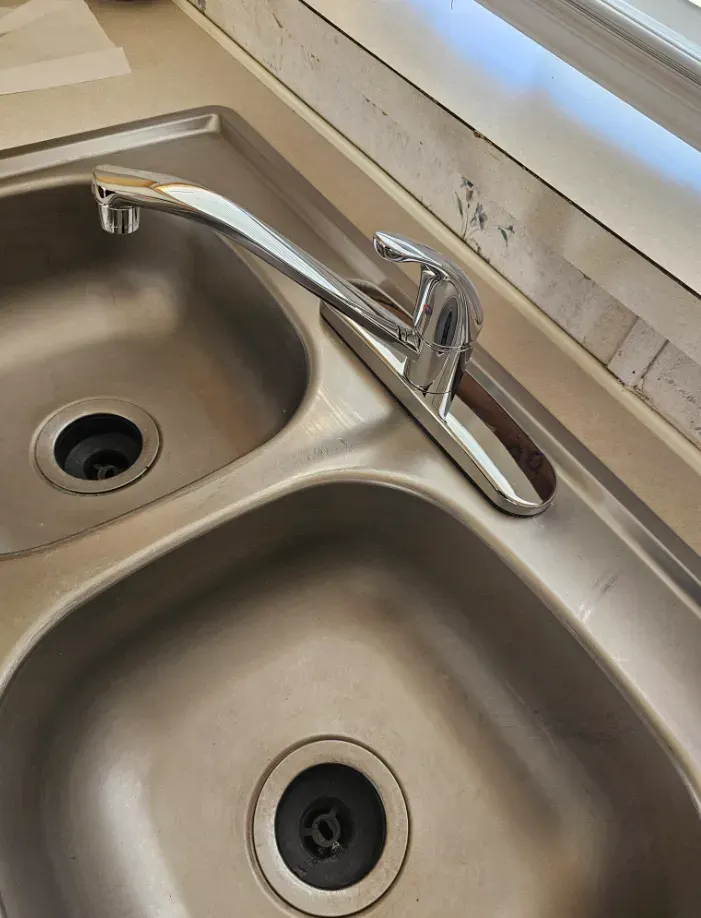 New kitchen faucet installed on a stainless steel sink