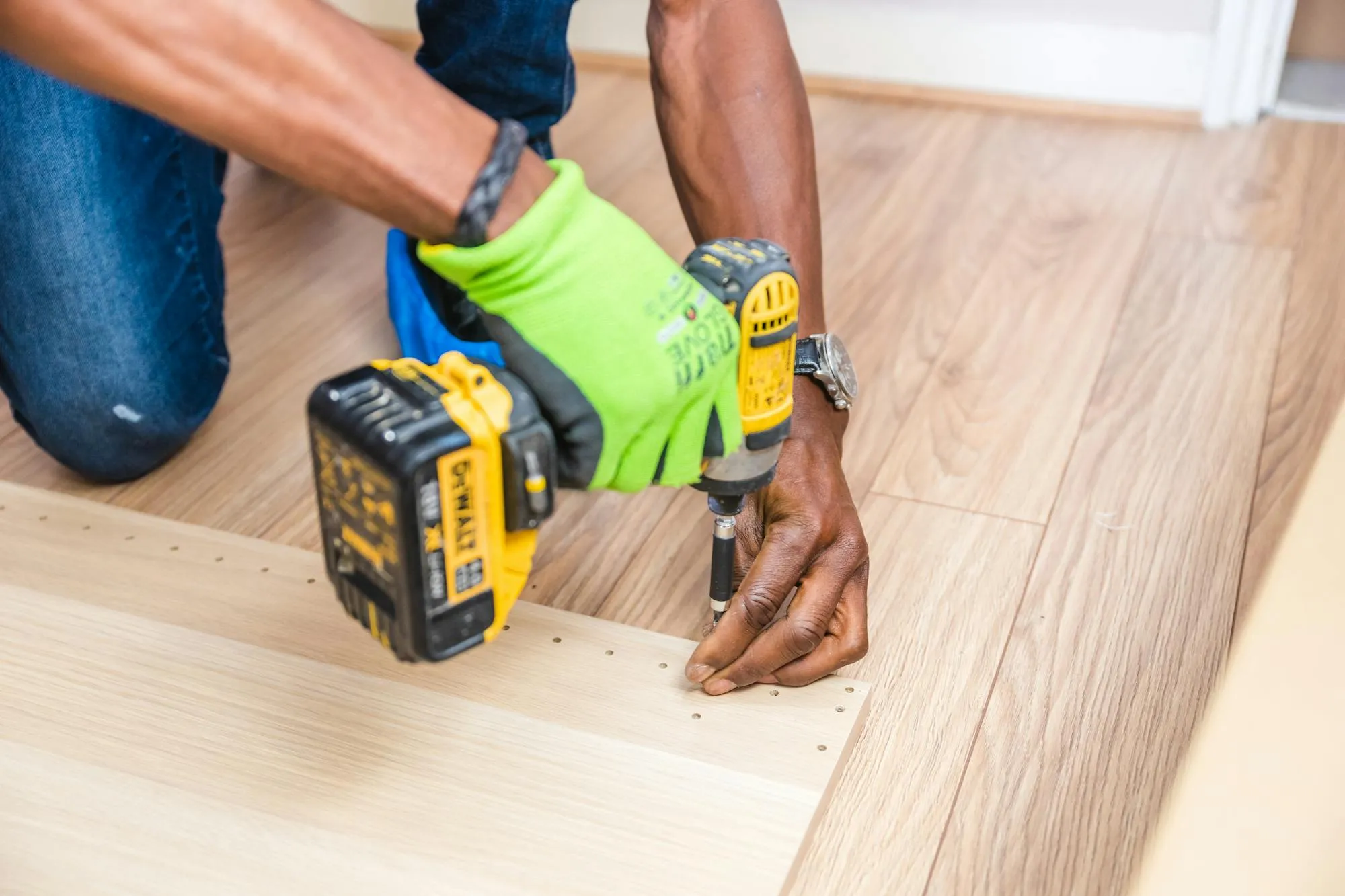 Handyman driving a screw into new wood flooring with a cordless drill